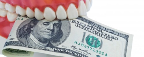 A pair of false teeth holding a one-hundred dollar bill.