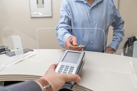 A patient using a credit card to pay for wisdom tooth extraction