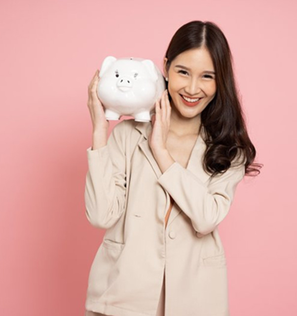 Woman on pink background holding a piggy bank and smiling