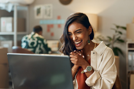Woman making a celebratory gesture and looking at her laptop