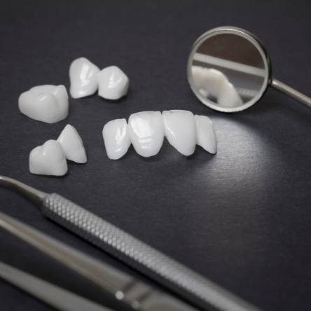 Prosthetic teeth and dental instruments on black surface