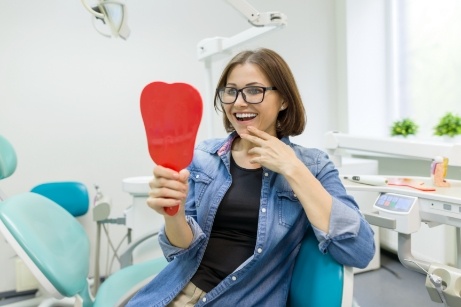 Woman sitting in dental chair looking into mirror