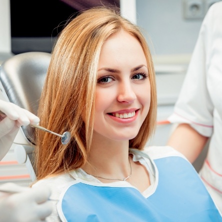 Blonde woman sitting in dental chair and smiling