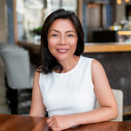 Woman in white shirt sitting at table and smiling