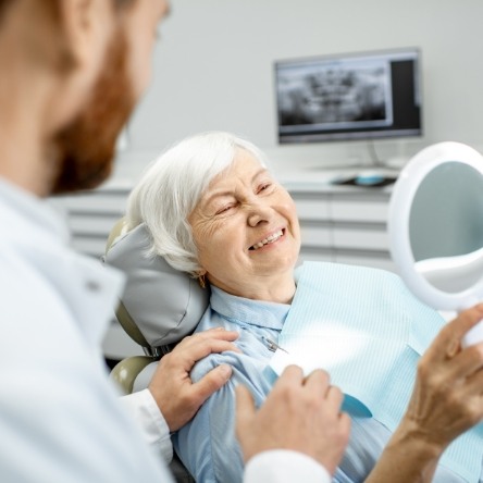 Senior female dental patient looking into handheld mirror