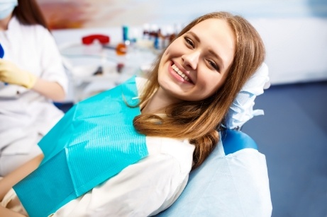 Woman leaning back in dental chair and smiling