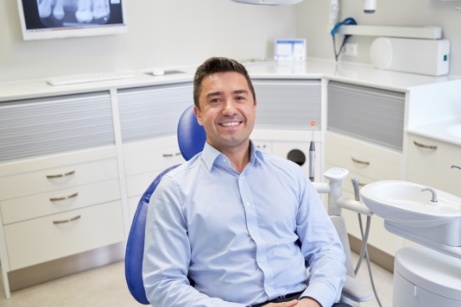 Man in light blue shirt smiling in dental chair