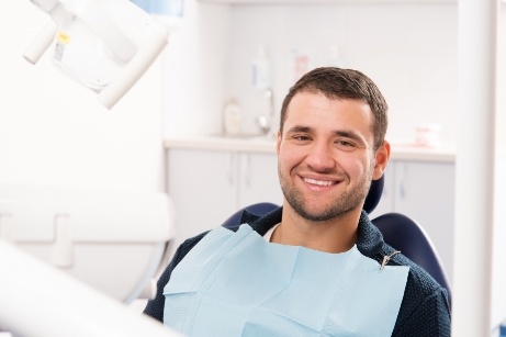 Young man sitting in dental chair and smiling