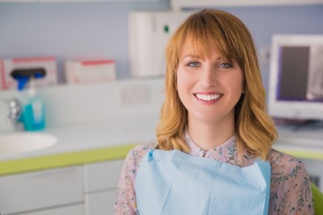 Orange haired woman sitting in dental chair and smiling