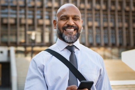 Man in tie standing outside building and smiling