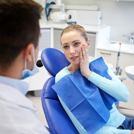 Blonde woman with tooth pain speaking to dentist