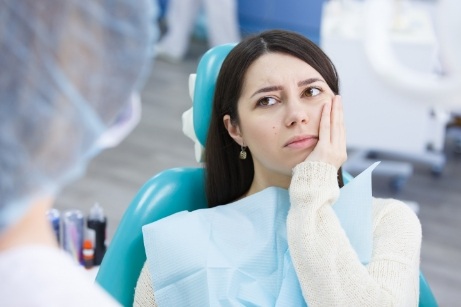 Woman with tooth pain looking up at dentist