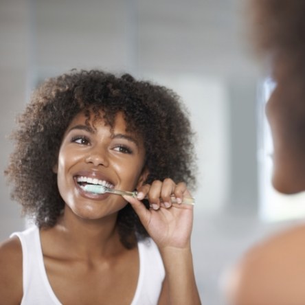 Woman in white shirt brushing her teeth