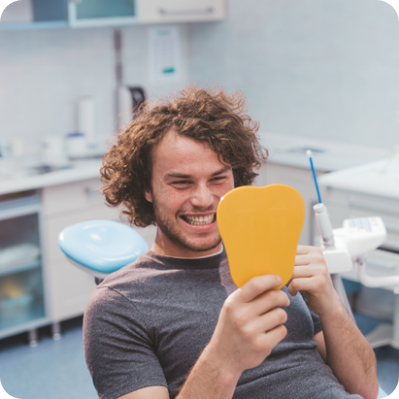Male dental patient checking smile in mirror