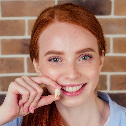 Red haired woman holding a tooth