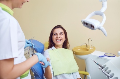 Woman sitting in dental chair shaking dentists hand