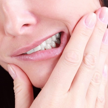 Woman rubbing jaw in need of wisdom tooth extraction in Mesquite