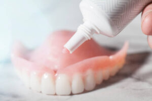 Cream adhesive being applied to a denture