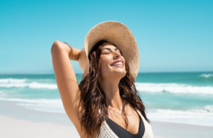 Woman tilting her head back on beach, smiling and relaxed