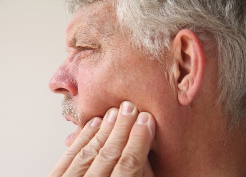 An older man suffering from wisdom tooth pain