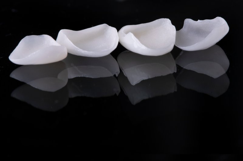 A closeup of porcelain veneers against a black background